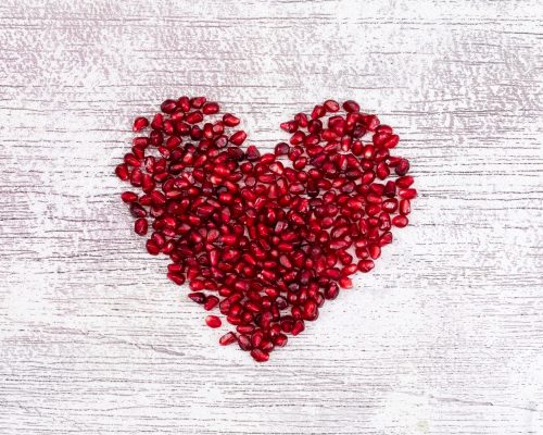 heart shaped pomegranate top view on white textured table